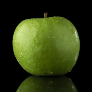A green apple in front of a black background