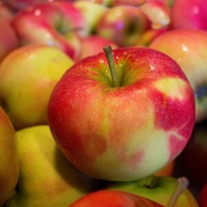 A Bunch of apples that are yellow with red over much of the yellow.
