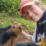 A young woman with a red ball cap petting a German Shepard dog